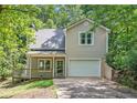 Charming home featuring a one-car garage and a cozy front porch, surrounded by lush trees at 3255 Marine Rd, Cumming, GA 30041