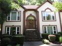 Inviting home entrance with stone steps, a decorative wreath, and manicured hedges leading to an arched doorway at 5820 Elm Tree Dr, Buford, GA 30518
