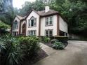 Two-story home with white siding, brown trim, lush landscaping, and a side-entry garage, nestled in a wooded area at 5820 Elm Tree Dr, Buford, GA 30518