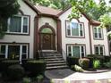 Beautiful home showcasing front door with an arched entry, manicured shrubs and stone steps at 5820 Elm Tree Dr, Buford, GA 30518