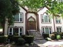 Exterior view of home featuring arched entryway, manicured shrubs, stone steps and lush foliage at 5820 Elm Tree Dr, Buford, GA 30518