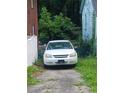 View of the front of the house and overgrown driveway with the car parked there at 3363 Lake Valley Nw Rd, Atlanta, GA 30331