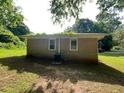 View of the back of the brick house with small yard and green grass surrounded by trees at 2369 Christian Cir, Covington, GA 30016