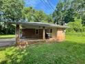 Exterior view of house showing the side brickwork and carport with lush green yard and trees at 2369 Christian Cir, Covington, GA 30016