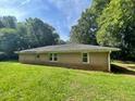 Back of ranch-style house with an expansive green lawn surrounded by mature trees in a serene setting at 2369 Christian Cir, Covington, GA 30016