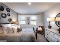 Cozy bedroom with neutral tones, featuring two windows, decorative wall art, and soft, inviting bedding at 3351 Orwell Way # 2301, Cumming, GA 30041