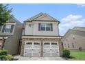 Charming townhome featuring a stone facade and two-car garage with decorative doors at 252 Stone Park Dr, Woodstock, GA 30188