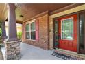 Inviting front porch showcasing brick accents, a red door, and stone columns, providing a warm welcome at 2532 Gloster Mill Drive Southwest, Lawrenceville, GA 30044