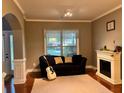 Cozy living room with hardwood floors, a decorative fireplace, a comfortable couch, and a bright window at 2532 Gloster Mill Drive Southwest, Lawrenceville, GA 30044