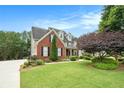A brick and gray two-story home, highlighting manicured landscaping, lush green lawn, and a welcoming facade at 4653 Glory Maple Trce, Powder Springs, GA 30127