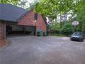 View of driveway with basketball hoop in backyard next to brick house with open garage at 5741 Wolf Laurel Ln, Lilburn, GA 30047