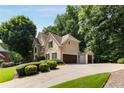 Tan two-story home with three car garage, stone accents, and beautiful landscaping at 820 Chelsea Park Ne Dr, Marietta, GA 30068