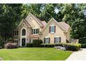 Charming front elevation of tan home with stone accents, black trim, and professionally landscaped yard at 820 Chelsea Park Ne Dr, Marietta, GA 30068