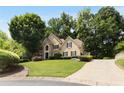 Two-story tan home with stone accents, mature trees, and driveway on professionally landscaped lawn at 820 Chelsea Park Ne Dr, Marietta, GA 30068