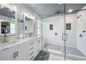 Modern bathroom with double vanity, white cabinets, glass enclosed shower with pebble floor, and tiled walls at 11352 Musette Cir, Alpharetta, GA 30009