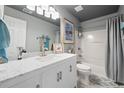 Bathroom featuring a white vanity, marble countertop, tub with shower, and calming blue accents at 11352 Musette Cir, Alpharetta, GA 30009
