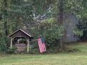 Rustic well house with an American flag flying on lush green property at 408 Hasty Trl, Canton, GA 30115