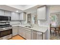 Bright kitchen with stainless steel appliances, gray cabinets, granite countertops, and pass-through to the dining area at 67 Middleton Se Ct, Smyrna, GA 30080