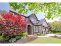 Charming two-story home featuring stone and brick, complemented by mature trees and colorful landscaping at 2720 Garonne Way, Cumming, GA 30041