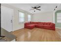 Bright living room featuring hardwood floors, large windows, and a cozy red sectional at 33 Russell Rd, Mcdonough, GA 30252