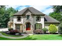 Charming two-story home with a stone facade, arched entryway, lush landscaping, and a well-maintained lawn at 2910 Creek Tree Ln, Cumming, GA 30041