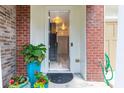 Charming home entrance with brick accents, colorful potted plants, and a welcoming view into the brightly lit foyer at 6426 Queens Court Trce # 7, Mableton, GA 30126