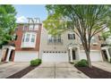 Attractive townhome exterior featuring an attached garage, brick and painted facade with mature trees at 11302 Musette Cir, Alpharetta, GA 30009