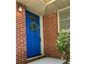 Close-up of bright blue front door with decorative wreath, brick exterior, and sidelight window at 1403 Dennis Dr, Decatur, GA 30032