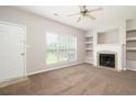 Cozy living room features plush carpeting, a fireplace, and built-in shelving at 6010 Capitol Knl, Fairburn, GA 30213