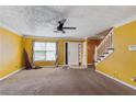 Inviting living area with a ceiling fan, textured ceiling, and stairs leading to upper level at 573 Hambrick Sq, Stone Mountain, GA 30083