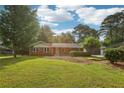 Quaint brick home with a lush front yard and mature trees surrounding the property at 1869 Hebron Hills Dr, Tucker, GA 30084