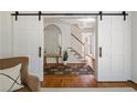 Open foyer with barn doors, wood floors, console table, arched mirror and view of the stairway at 6960 Hunters Branch Dr, Atlanta, GA 30328