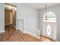 Bright foyer with wood floors, white banister, and decorative front door with complementing arched window above at 4077 High Country Dr, Douglasville, GA 30135