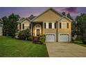 Charming two-story home at twilight featuring manicured lawn, two car garage, and classic front door with decorative window at 4077 High Country Dr, Douglasville, GA 30135