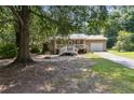Quaint ranch home featuring a metal roof, white-railed front porch, and an attached garage, surrounded by trees at 136 Pine St, Covington, GA 30014