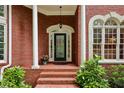 Inviting front entrance featuring a decorative glass door, red brick stairs, and lush landscaping with green plants at 770 Spalding Heights Dr, Atlanta, GA 30350