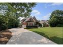 Long concrete driveway leading to a brick home surrounded by mature trees at 390 Wilde Green Dr, Roswell, GA 30075