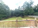 Fenced-in backyard with a wooded perimeter and basketball hoop, as seen from the wood deck at 350 Glynnshire Ct, Covington, GA 30016