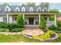 Inviting front porch featuring double doors, stately columns, manicured shrubs, stone pathway and a well-kept lawn at 505 Junction Pt, Roswell, GA 30075