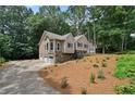 Two-story tan house with stone foundation and a three-car garage on a wooded lot at 400 Hunt River Way, Suwanee, GA 30024