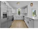 Bright kitchen with stainless steel refrigerator, white cabinetry, and marble countertops at 400 Hunt River Way, Suwanee, GA 30024
