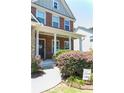 Inviting front entrance with a covered porch, brick facade, decorative bushes, and a walkway at 6695 Grove Meadows Ln, Cumming, GA 30028