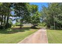 Home featuring a long driveway surrounded by mature trees and a lush green lawn at 28 Fawn Ct, Sharpsburg, GA 30277