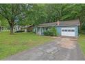 View of a light blue home with a well-kept lawn and an attached garage and mature trees at 5012 Galbraith Cir, Stone Mountain, GA 30088
