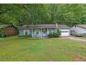 Quaint light blue home with a white picket fence and attached garage nestled among mature trees at 5012 Galbraith Cir, Stone Mountain, GA 30088