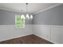 Dining area with hardwood floors, white wainscoting, contemporary chandelier, and large window at 856 Bridgewater Sw St, Atlanta, GA 30310