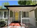 Inviting covered front porch with a bright yellow front door and white railing at 921 Hemingway Rd, Stone Mountain, GA 30088