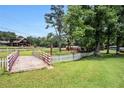 Wooden bridge in the yard, with a red barn, a pond and white fence in the background at 677 Panola Rd, Ellenwood, GA 30294
