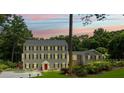 Charming traditional home with a symmetrical facade, lush lawn, and illuminated windows at dusk at 555 Valley Hall Dr, Atlanta, GA 30350