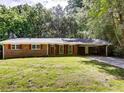 Charming brick home featuring red shutters, a well-manicured lawn, and a convenient carport at 5533 Glore Sw Dr, Mableton, GA 30126